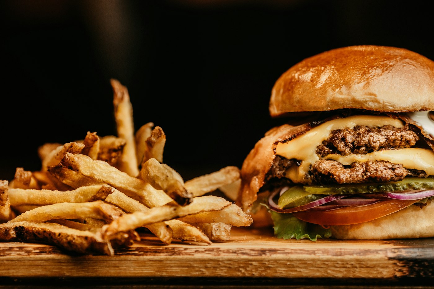 Burger mit Pommes auf Holzbrett, Startseite des Imbiss Musterplatz (Beispielbild)